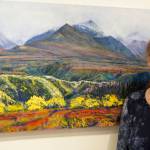 The long view Homer artist Rita Pfenninger poses last Friday for the opening of her show, Mountain, Foliage, Ocean, Sky at Fireweed Gallery. The painting shows the Chugach Mountains as seen from Sheep Mountain Lodge, Glenn Highway. Also in the show is jewelry by her husband, Larry Hoare.
