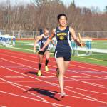 Photo by Megan Pacer/Homer News Homer&rsquo;s Kailee Veldstra crosses the finish line of the girls&rsquo; 400-meter relay to claim first place for her team Friday, April 13 at Homer High School.