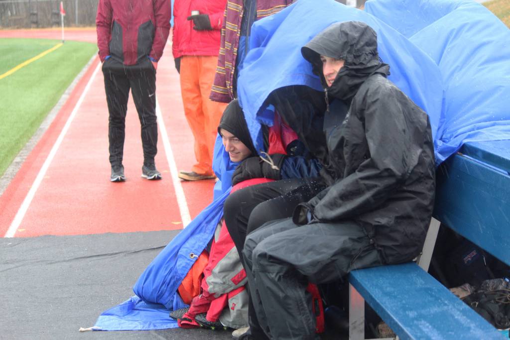 Members of the Homer High School soccer team huddle under raincoats and tarps as hail pours down during their game against Kenai Central High School on Tuesday, April 24, 2018 in Homer, Alaska. (Photo by Megan Pacer/Homer News)