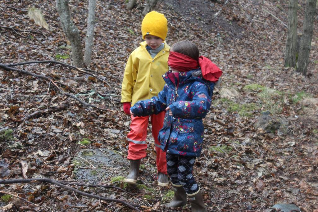 Riggs Harness coaches classmate Violet Pinsky through the woods while blindfolded during a game designed to teach them how animals communicate with each other on Tuesday, April 24, 2018 at Little Fireweed Academy on Homer, Alaska. Students played the games under the supervision of the Homer High School mentors who created them. (Photo by Megan Pacer/Homer News)