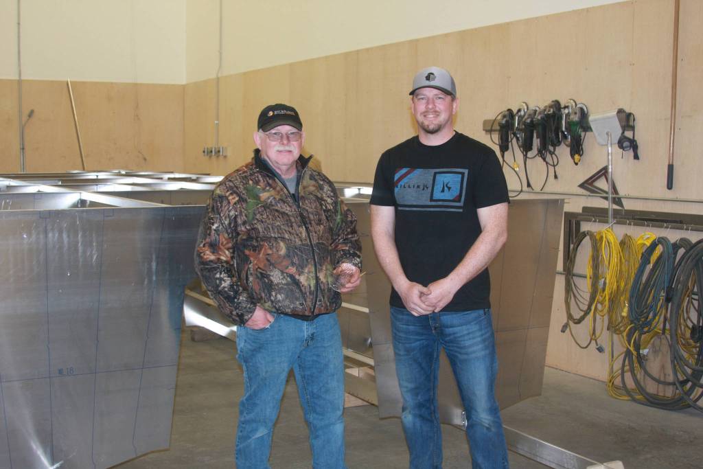 Eric Engbretsen (right), general manager of Bay Weld Boats, poses with his father Allen (left) in front of Bay Weld&rsquo;s 200th boat, the Catamaran dedicated to be Allen&rsquo;s personal recreational boat, at the celebration on Saturday, April 21 in Homer, Alaska. (Photo by Delcenia Cosman)