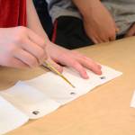 A Ninilchik School student uses a paint brush to dab carrot seeds contained in a glob of flour mixture onto a spread of toilet paper, essentially making a seed tape, Tuesday, May 1, 2018 at the school in Ninilchik, Alaska. Fourth, fifth and sixth graders got a visit from the Ninilchik chapter of the National FFA Organization, who gave them a lesson in planting in honor of Alaska Agriculture Day. (Photo by Megan Pacer/Homer News)