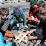 The sunny afternoon of May 2 is perfect weather for an afternoon at the beach. Laying the groundwork for a fire on which to steam a pot of stinging nettles collected earlier in the day are (left to right) Wilderness Explorers Gracie Miotke, Johannes Bynagle, Mavricky Kulikov, Ellis Lorentz, Lars Dickson, and adult volunteer Derek Bynagle. (Photo by McKibben Jackinsky)