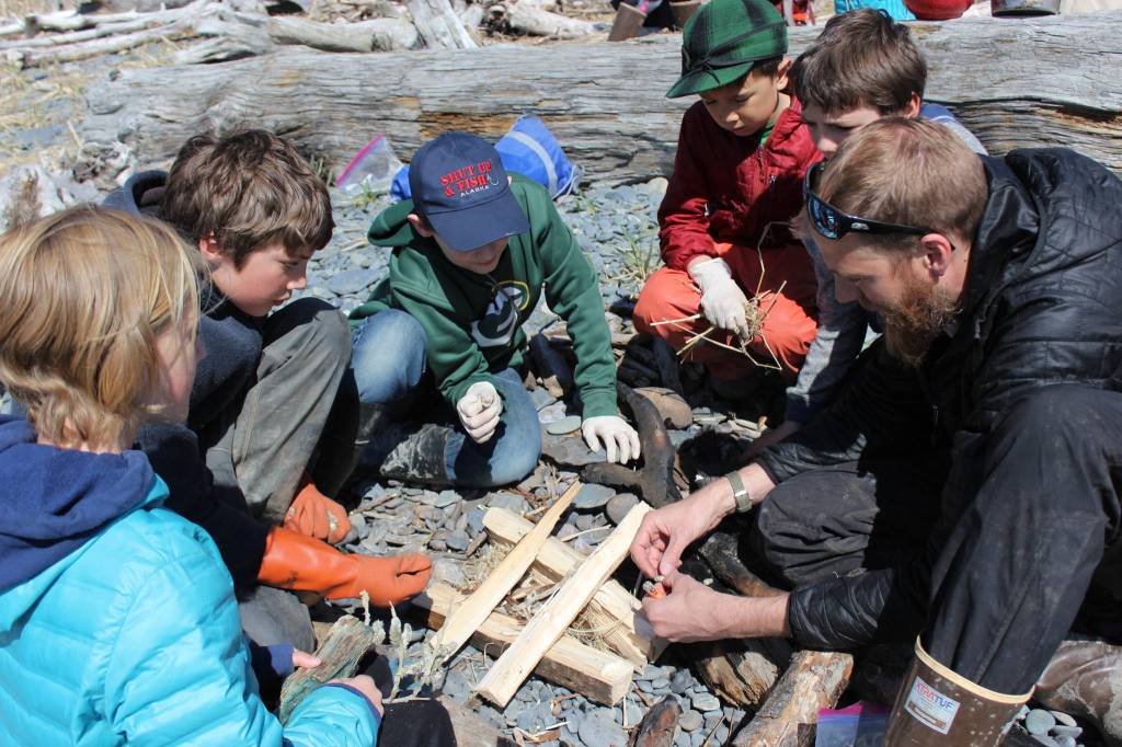 The sunny afternoon of May 2 is perfect weather for an afternoon at the beach. Laying the groundwork for a fire on which to steam a pot of stinging nettles collected earlier in the day are (left to right) Wilderness Explorers Gracie Miotke, Johannes Bynagle, Mavricky Kulikov, Ellis Lorentz, Lars Dickson, and adult volunteer Derek Bynagle. (Photo by McKibben Jackinsky)