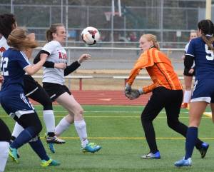 Homer goalkeeper Kelli Bishop (in orange) knocks the ball away on a Kenai Central rush Tuesday evening at Ed Hollier Field in Kenai. (Photo by Joey Klecka/Peninsula Clarion)