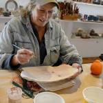 Beth McKinney paints a plate for Bunnell Street Arts Center&rsquo;s annual Plate Project. (Photo provided)