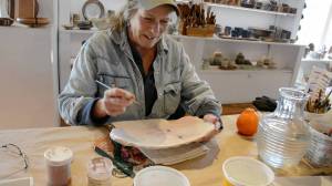 Beth McKinney paints a plate for Bunnell Street Arts Center&rsquo;s annual Plate Project. (Photo provided)