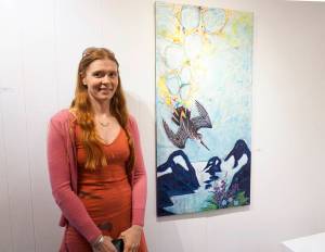 Erin Rae D&rsquo;Eimon stands by one of her paintings at the First Friday opening for her show on May 4, 2018 at the Homer Council on the Arts in Homer, Alaska. (Photo by Michael Armstrong/Homer News)