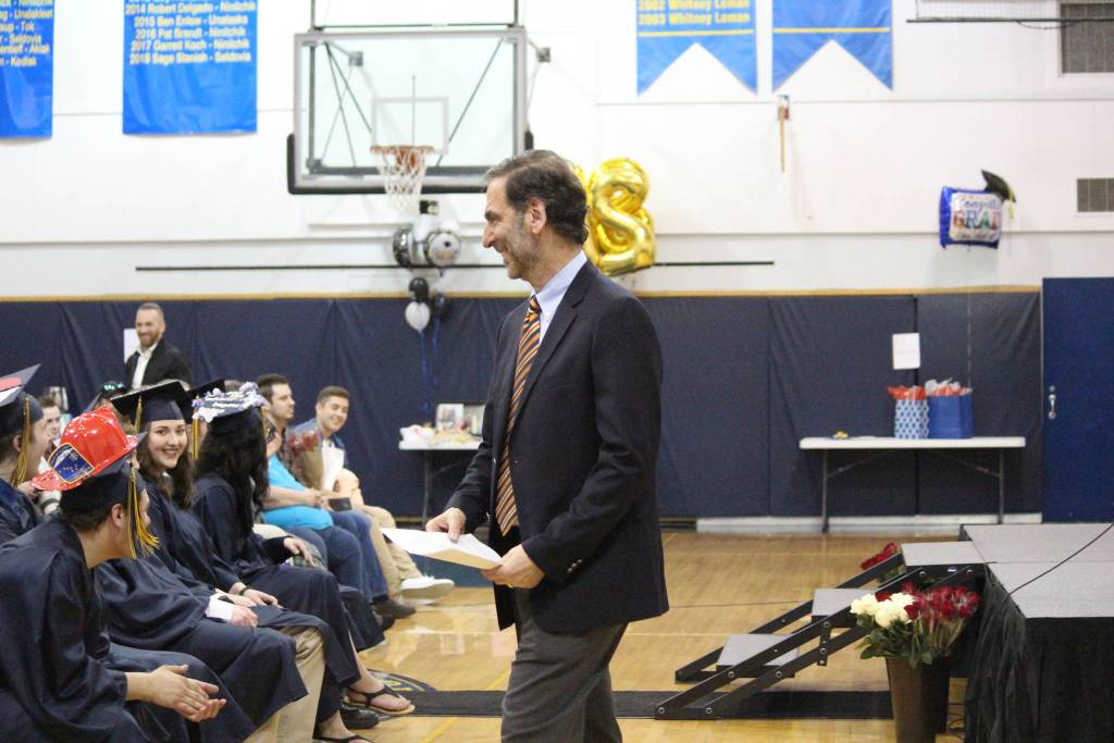 Loren Leman, a 1968 Ninilchik School graduate and speaker for the current graduation class&rsquo;s Monday, May 21, 2018 ceremony, walks back to his seat after returning a page of salutatorian Chelsea Oberle-Lozano&rsquo;s speech that he accidentally took off the podium after his own speech. (Photo by Megan Pacer/Homer News)