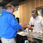 Photo by Megan Pacer/Homer News Former Homer City Council member David Lewis shows his ID to Aaron Stiassny on the opening day of Homer&rsquo;s first marijuana retail store, Uncle Herb&rsquo;s, on Thursday, May 24 in Homer. Stiassny will oversee the business for his father, Lloyd, who owns another branch in Anchorage.