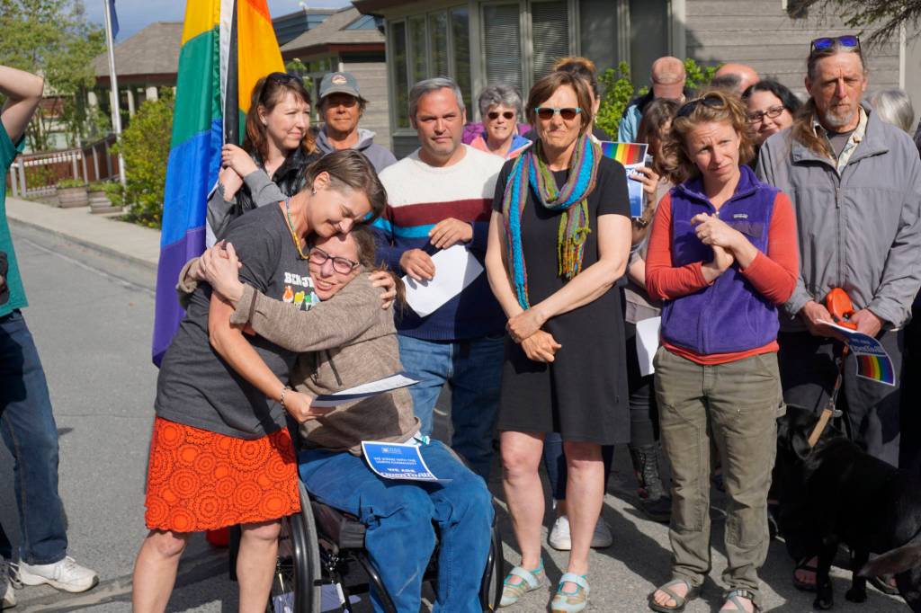 Catriona Reynolds, left, hugs Tess Dally, right, after Homer Mayor Bryan Zak read a Mayoral Recognition recognizing June as Homer Pride Month at about 6 p.m. Monday, June 11, 2018 outside Homer City Hall in Homer, Alaska. A crowd of about 75 people attended in support of Pride Month. Council members Shelly Erickson, Heath Smith and Thomas Stroozas notified the city clerk that they would not attend the June 11 meeting, forcing its cancellation because of lack of a quorum. Listening are council members Donna Aderhold, third from right, and Rachel Lord, second from right. (Photo by Michael Armstrong/Homer News)