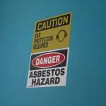 A sign warning of asbestos hazard marks a door in one of the two Homer Education and Recreation Complex buildings, shown here Tuesday, June 26, 2018 in Homer, Alaska during a walk-through of the complex with the HERC task force, members of the public and city staff. One of the two buildings cannot currently be used by anyone but city staff. (Photo by Megan Pacer/Homer News)