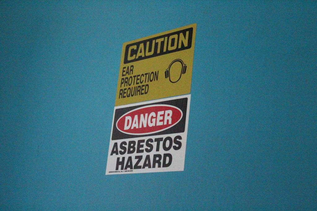 A sign warning of asbestos hazard marks a door in one of the two Homer Education and Recreation Complex buildings, shown here Tuesday, June 26, 2018 in Homer, Alaska during a walk-through of the complex with the HERC task force, members of the public and city staff. One of the two buildings cannot currently be used by anyone but city staff. (Photo by Megan Pacer/Homer News)