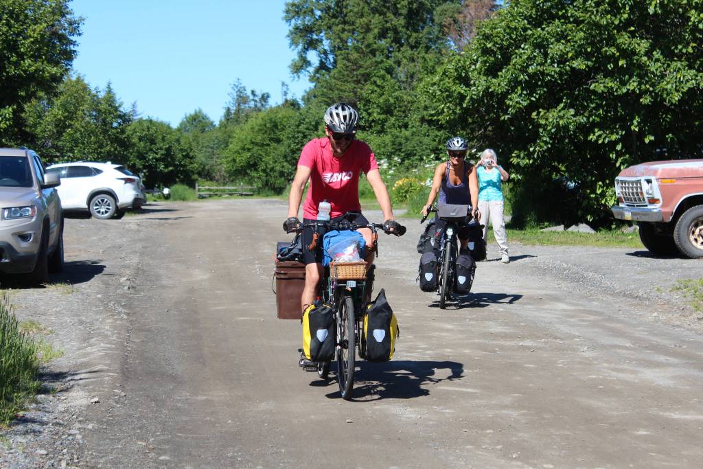 Chris Haag and Sophie George take off on their bikes from a rental on Hidden Way, with Haags grandmother taking a photo as they go, on Monday, July 2, 2018 in Homer, Alaska. The husband and wife are traveling by bike from Alaska to Argentina, a trip estimated to take two years. (Photo by Megan Pacer/Homer News)
