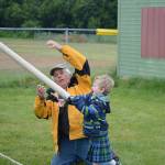Torrin Bartlett tosses the caber (a cardboard tube) during the childrens events in the July 3, 2017 Kachemak Bay Scottish Club Games at Karen Hornaday Park as Dave Brann, left, watches. (Photo by Michael Armstrong/Homer News)