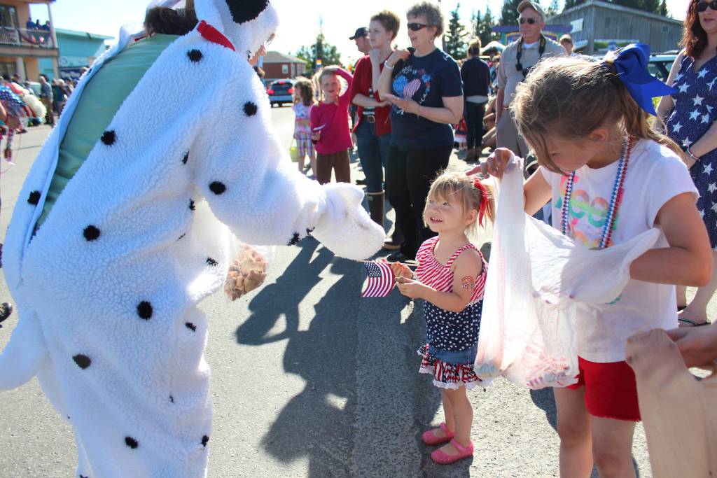 A member of the Homer Animal Friends hands out a dog treat to a young girl during this years Independence Day parade Wednesday, July 4, 2018 in Homer, Alaska. (Photo by Megan Pacer/Homer News)
