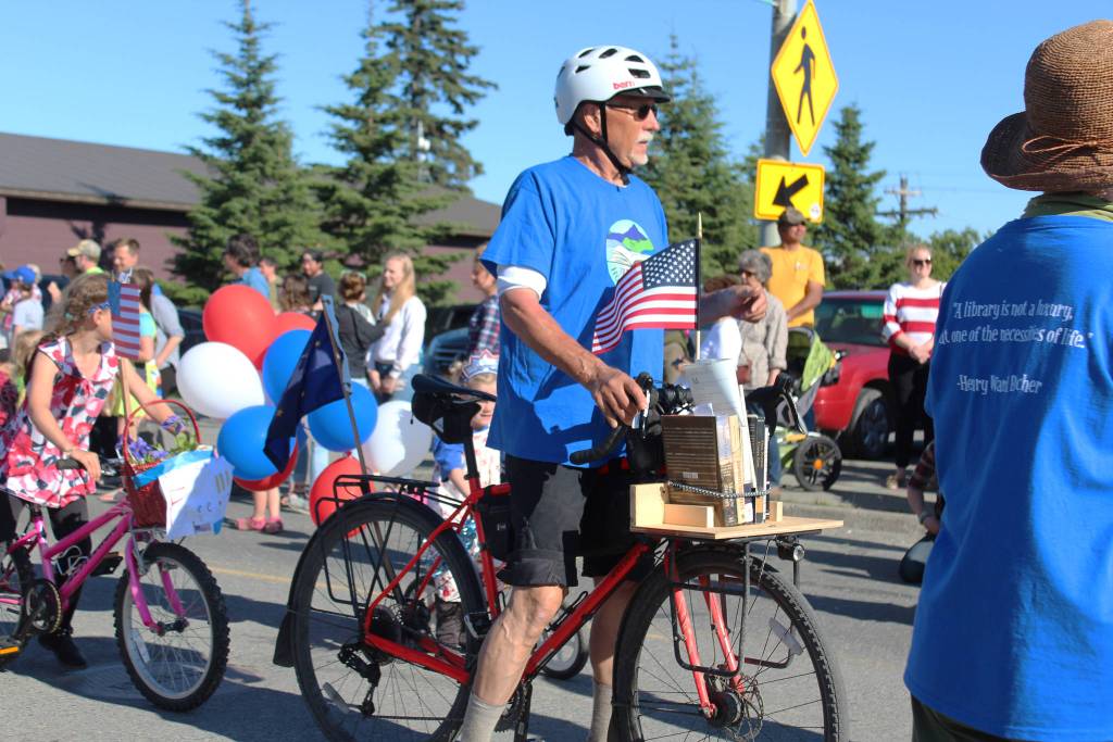 Wayne Adderhold moves along with the Friends of the Homer Library during this years Independence Day parade Wednesday, July 4, 2018 on Pioneer Avenue in Homer, Alaska. The friends handed out books to children as they marched and performed their own book-focused dance. (Photo by Megan Pacer/Homer News)