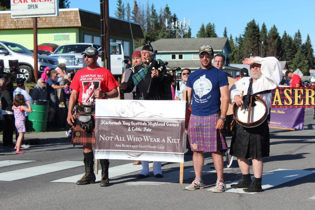 Members of the Kachemak Bay Scottish Club march in this years Independence Day parade Wednesday, July 4, 2018 with a banner advertising the annual Kachemak Bay Scottish Highland Games and Celtic Fair, on Pioneer Avenue in Homer, Alaska. (Photo by Megan Pacer/Homer News)