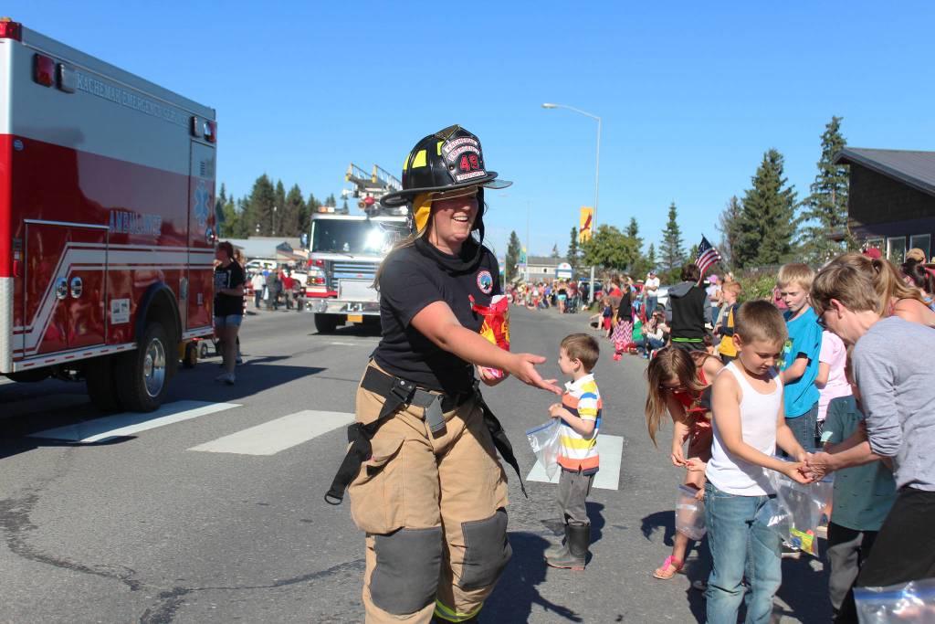 A member of Kachemak Emergency Services tosses candy to eager children along Pioneer Avenue during this years Independence Day parade Wednesday, July 4, 2018 in Homer, Alaska. (Photo by Megan Pacer/Homer News)