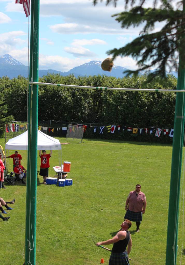 Zachary Fraley of Homer looks over his shoulder to chart the progress of a sheaf he tossed from a pitchfork, with the goal of getting it over the standard pole above him, at the Kachemak Bay Scottish Highland Games on Saturday, July 7, 2018 at Karen Hornaday Park in Homer, Alaska. (Photo by Megan Pacer/Homer News)