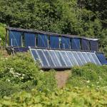 Several solar panels rest in the sun up an incline at the Dean family farm Friday, July 6, 2018 at their home off East End Road near Homer, Alaska. Artist Jeff Dean uses solar power to supplement a boiler system in place at their home, which was part of the annual Homer Solar Tour this year. (Photo by Megan Pacer/Homer News)