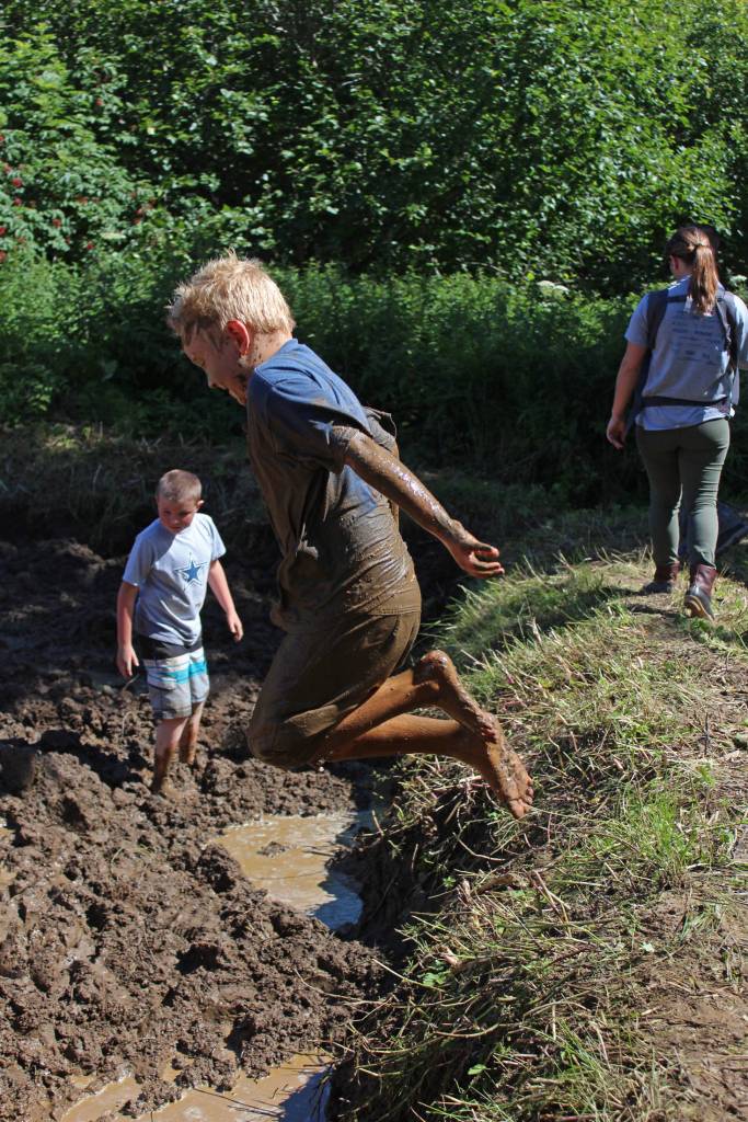 Sailor Clapp, 7, of Texas, leaps into a pit of mud during this years Mud Games on Sunday, July 22, 2018 at Cottonwood Horse Park on East End Road in Homer, Alaska. He and his mother are visiting for the summer. (Photo by Megan Pacer/Homer News)