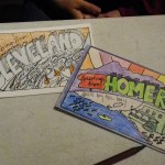A “Greetings from Homer” postcard colored by Jenny Stroyeck of Homer is next to a Cleveland card. Emery encouraged Homer residents to visit Bunnell Street Arts Center and color Homer postcards to exchange with Cleveland area residents.-Photo by Michael Armstrong, Homer News