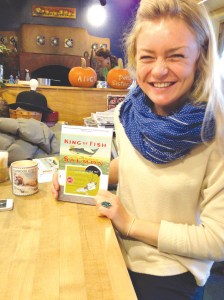 Emma Laukitis holds up a copy of David Montgomery’s book “King of Fish: The Thousand-Year Run of Salmon” during the Salmon Project’s book drop at Two Sisters Bakery on Sunday.