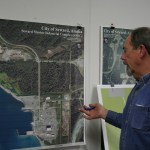 Seward Community Development Director Ron Long discusses the city’s plans for the Seward Marine Industrial Center across Resurrection Bay from its population center in front of a photo of the shipyard and surrounding area.
