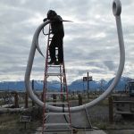 Bay Welding’s Brad Howe caps 3 1/2-inch holes used to fill the circle hook sculpture with concrete to keep it from shuddering in a stiff breeze.-Photo by Miranda Weiss