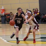 Nikolaevsk Warrior Megan Hickman, 25, maneuvers the ball down the court beyond the reach of Akiak Thunderbolt’s Miranda Demientieff during team competition at the State 1A tournament in Anchorage on Saturday.-Photo by McKibben Jackinsky