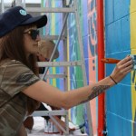 Spellar mural group painter Bailey Gamble paints part of a pattern on the Star Car Wash mural, the first mural of Bunnell Street Art Center’s Peonies on Pioneer public art campaign.-Photo by Anna Frost, Homer News
