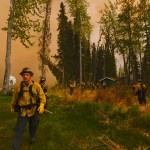 Central Emergency Services firefighters, dwarfed by 150 foot flames and thousands of feet of smoke, assess whether they can protect a property near the intersection Fisherman's Road and Killey Street Sunday May 25, 2014 in the Funny River community of Soldotna, Alaska. A 156,041 acre wildfire has been threatening the community — which was largely evacuated late Sunday — for four days.-Photo by Rashah McChesney/Morris News Service-Peninsula Clarion
