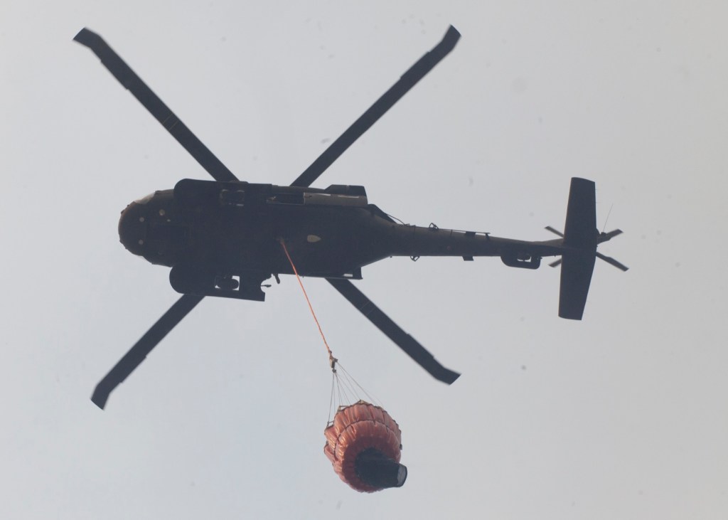 A Black Hawk helicopter prepares to drop a bucket of water on a hot spot of the Funny River Horse Trail wildfire that encroached into the Funny River community, Sunday May 25, 2014, in Soldotna, Alaska. The wildfire has burned more than 156,041 acres of Kenai National Wildlife Refuge land and threatens the communities of Kasilof, Funny River, Soldotna, Sterling and Bear Creek.