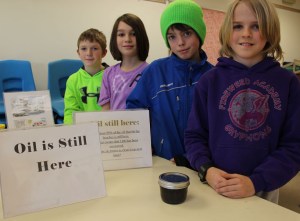 Oil from the Exxon oil spill remains on Prince William Sound beaches. As proof, Harrison Metz, Coda Wood, Terry Gilliland and Austin Cline have a jar of the oil collected from Eleanor Island during August 2013.-Photo by McKibben Jackinsky, Homer News