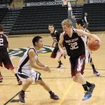 Nikolaevsk's Neil Gordeev, 32, keeps a firm grip on the ball, while teammates Kalenik Molodih, 2, and Nikit Fefelov, 23, keep an eye on the action in the game with the Manokotak Lynx for the 1A State fourth-place title.-Photo by McKibben Jackinsky, Homer News