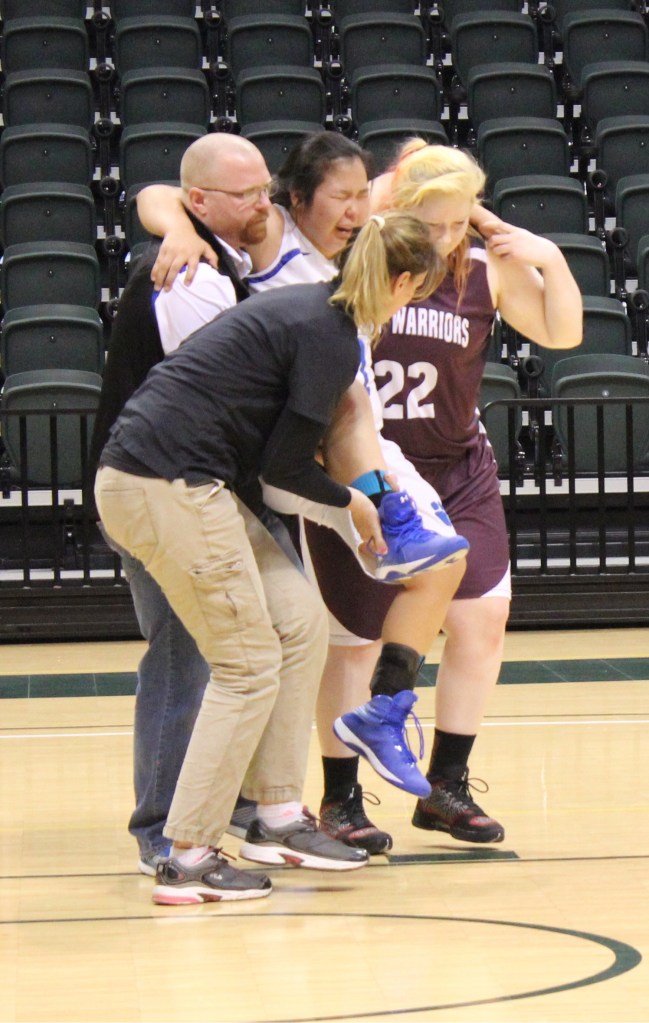 Nadejda Gordeev, 22, of the Nikolaevsk Warriors, helps an injured Newhalen Malamute player off the floor.-Photo by McKibben Jackinsky, Homer News