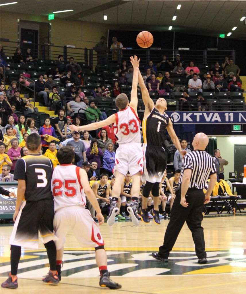 Seldovia's Aidan Philpot, 33, gives the Otters the tip off in the 1A State championship game against the Scammon Bay Eagles. Teammate Chance Haller, 25, waits for the action to begin.-Photo by McKibben Jackinsky, Homer News