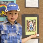 Aaron Koch, a first grade student, stands next to his painting, “The Racer Snowman.”