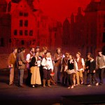 Katelyn Wythe, center, holding books, is one of the student revolutionaries in “Les Misérables.” Wythe also was in the 2003 Homer High school production. Jennifer Norton, Bobby Copeland-McKinney, Judy Wynn and Jill Berryman painted the city-scene backdrop. -Photo by Michael Armstrong, Homer News