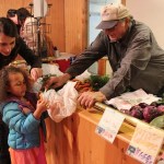 In photo at right, Megan Palma and 4-year-old Aria Palma purchase carrots from local farmer Robert Durr on opening day of Alaska Wild Berry Emporium.