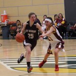 Nikolaevsk Warrior Megan Hickman, 25, maneuvers the ball down the court beyond the reach of Akiak Thunderbolt’s Miranda Demientieff during the State 1A tournament in Anchorage on March 14.-Photo by McKibben Jackinsky