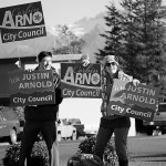 Josh Garvey, left, and Elizabeth Garvey wave signs for Corbin Arno and Justin Arnold during the evening rush hour on Pioneer Avenue on Tuesday.-Photo by Michael Armstrong, Homer News