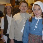 Fireweed Academy students Anthony Melkomukow, in the role of Kondraty Fefelov, a Russian mechanic; Noah Irons, as Wolfgang, a German musician; and Bea Strobel, as Victoria Gurka, a Polish seamstress, wait for a documentation as they role-play being immigrants arriving at Ellis Island during a recent lesson at Fireweed Academy.-Photo provided