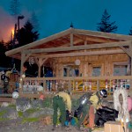 Flames shoot up in woods behind a cabin on Hesketh Island as wildland firefighters prepare to attack the fire.  -Photos by Heather Ericson