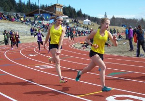 Tayla Cabana, left, hands off the baton to Cassidy Soistman in the 4x200 meter relay in Homer on Saturday.-Photo by McKibben Jackinsky, Homer News