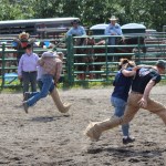 Two teams in the 40-and-older category dash across the Ninilchik Rodeo arena in Saturday’s three-legged race.-Photo by McKibben Jackinsky, Homer News