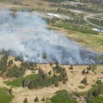 This aerial photo of the Sandra Street fire shows flames burning through grass just west of the Kachemak Emergency Services McNeil Canyon Fire Station, right, and McNeil Canyon Elementary School, center.                              -Photo by Alaska Division of Forestry