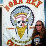 Annie Malloy, finish line coordinator for the Hoka Hey Motorcycle Challenge, poses by the Hoka Hey sign at the end of the Homer Spit.-Photo by Michael Armstrong, Homer News