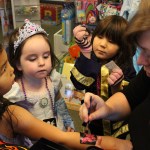 Princess Aliyah Adams is given a sparkly butterfly tattoo done by Marian Ford while Mara Adams and Rei Beams look on.-Photo by McKibben Jackinsky, Homer News